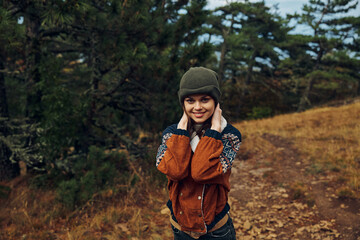 Happy young woman smiling on a scenic autumn hiking trail through the forest surrounded by colorful foliage