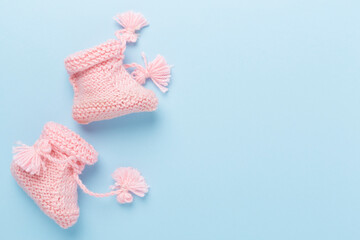 Pink baby booties on color background, top view