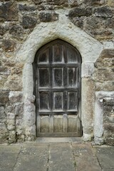 An Ancient wooden door in a stone castle wall. England, UK. 