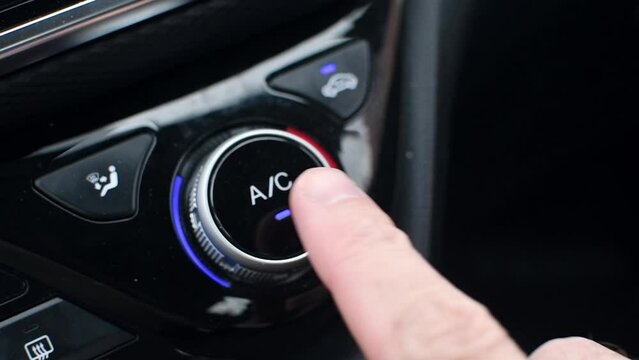 Man's hand presses round button to turn off air conditioner in car. Turning off the air conditioner in the car.