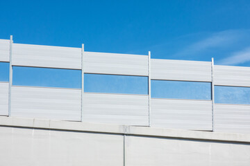 Soundproof shields for the road fencing at the descent from the overpass. There is a blue sky....