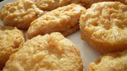 A chicken nugget is a small piece of chicken, either ground or whole, coated in batter or breadcrumbs, then deep-fried or baked until crispy. Shot with 24mm probe macro lens. Fast-food background. 
