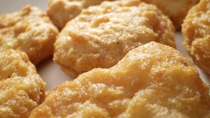 A chicken nugget is a small piece of chicken, coated in batter or breadcrumbs, and deep-fried or baked, often served as a fast-food snack. Shot with 24mm probe macro lens. Food background. 
