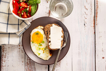 Fried eggs in plate with tomatoes salad and cheese sandwich for breakfast