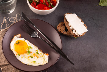Fried eggs in broun plate with cheese sandwich and tomatoes salad  for breakfast