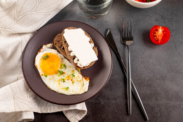 Fried eggs in broun plate with cheese sandwich and tomatoes salad  for breakfast