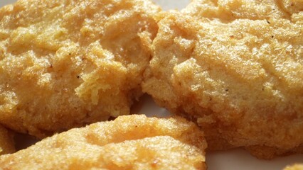 Chicken nuggets served with dipping sauces like ketchup, barbecue, honey mustard, or ranch. Enjoyed alone, in combos at fast-food spots, or in salads and wraps. Fast-food background. 
