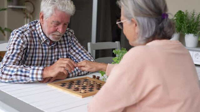 Pensioners pastime at senior home. Aged couple playing checkers. Activities for seniors, elderly active lifestyle, older people time spending concept
