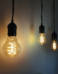 Three vintage light bulbs hanging from the ceiling, glowing warmly against a dim background. The filament patterns vary, adding an artistic touch to the minimalist design.