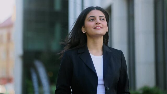 Successful beautiful young indian businesswoman looking around while walking down the city centre Smiling female go to or leaves work after great workday outdoors Beautiful day concept