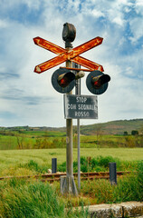 One old railway traffic light with a stop sign in Italian stands next to the rails among fields and...