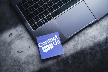Adhesive note on laptop with Contact Us concept. Customer support hotline people connect.