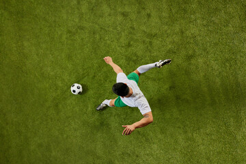 Dynamic aerial view photo of soccer player in mid-motion, preparing to kick the ball on well-maintained field. Concept of professionals sport, competition, tournament, energy, action. Ad
