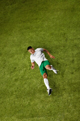 Dynamic photo of young sporty man, soccer player in mid-action, demonstrating hisskills on lush green sports field. Concept of professionals sport, competition, tournament, energy, action. Ad