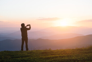 Man Taking Photo of Sunset on Mountain Peak