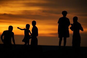 Silhouette of a group of local Papua people enjoying sunset at the beach.