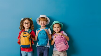 Group of happy children with colorful backpacks, smiling and ready for back to school on a vibrant blue background.