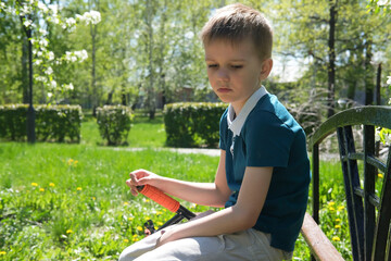 Boy is crying alone in park on bench, sitting and sad because of broken scooter. Child broke toy...