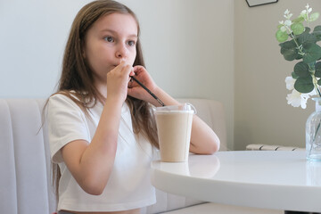 Happy carefree child on vacation enjoying cup of hot chocolate, cocoa, milkshake in cafe. Selective...