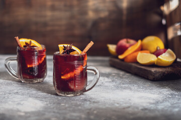 Two cups of mulled wine with spices, on the table. On the background of fruits. place for text
