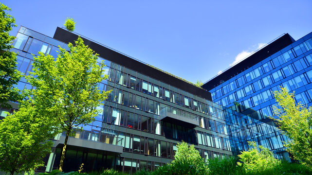 Sustainable glass office building with trees for reducing carbon dioxide. Eco-friendly building in modern city. Office with green environment. Corporate building reduce CO2.