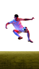 Dynamic shot of young guy dressed sportswear leaping in air to kicks ball in neon light against white studio background. Concept of professionals sport, competition, tournament, energy, action. Ad