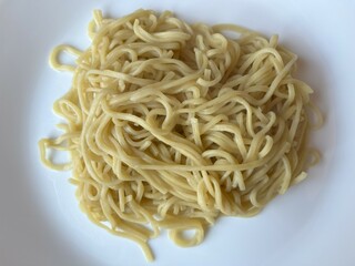 Close up cooked Chinese egg noodles on white plate top view