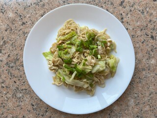 Top view cooked Chinese egg noodle with egg and vegetables on white plate 