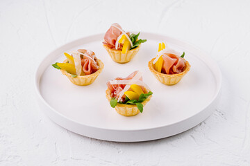 Gourmet prosciutto and melon canapes on white plate