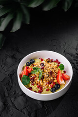 Fresh fruit and granola bowl on dark background