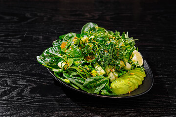 Fresh green spinach salad on dark wood table