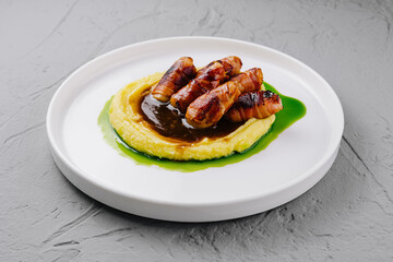 Bacon-wrapped sausages on mashed potatoes with gravy