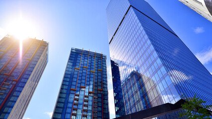 Bottom view of modern skyscrapers in business district against blue sky. Looking up at business buildings in downtown.