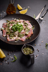 tuna carpaccio - slices of fresh raw tuna fillet on black ceramic plate