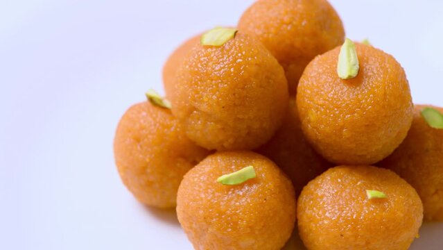 
Delicious looking Motichur ladoos (motichoor) stacked up on a plate. Toppish shot of motichur laddoos rotating slowly against white . Yummy looking indian sweets . Ladoos with pistachio topping.
