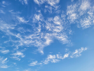 Blue sky background with fluffy feathery clouds