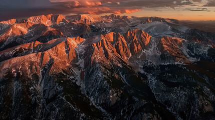 Obraz premium Aerial view of a sunset over a mountain range with clouds overhead
