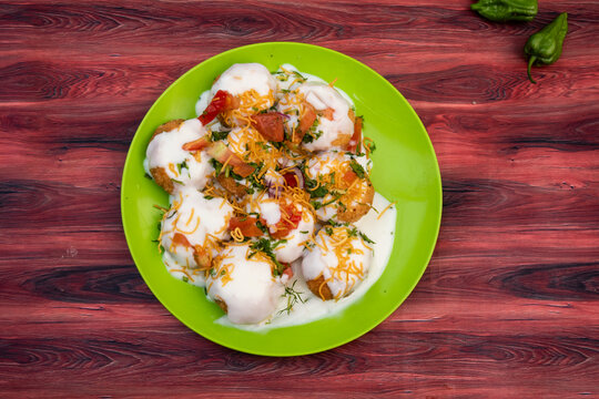 Doi Fuchka, pan puri, or gol gappa filled with herbs with spicy water served in plate isolated on wooden table top view of bangladeshi street food