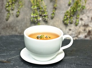 Glass of fresh tea from thyme, lat. Thymus vulgaris on the stone. Traditional curative thyme tea with many medical benefits.
