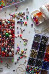Colorful beads, letter beads, threads and other jewelry making supplies on white background. Making friendship bracelets concept. Flat lay.