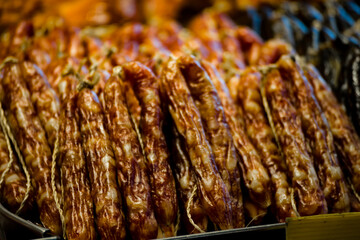 a close-up of Chinese-style sausages hung in an orderly fashion at a market stall