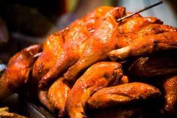 a market stall where roasted chicken legs are being sold