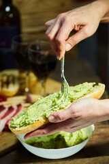 The process of spreading Guacamole on grilled bread. A dish of avocado and vegetables.