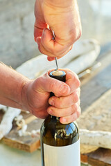 The process of opening a bottle of white wine with a corkscrew.