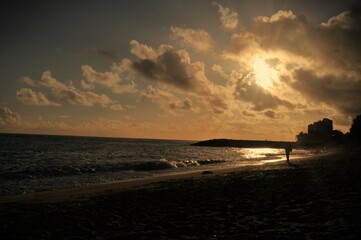 Atardecer en la playa con persona paseando