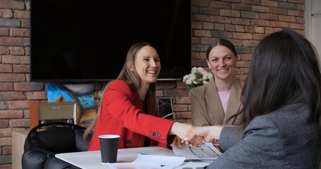 Women designers confirm deal shaking hands with client smiling. Female professional design team...