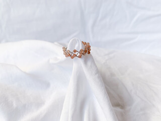 Handmade ring with rose quartz beads on white background.