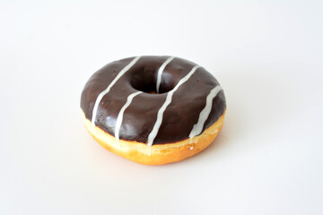 a chocolate frosted donut with white stripes on white background 