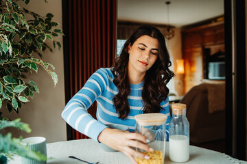 One young caucasian woman is eating corn flex breakfast at home before work	
