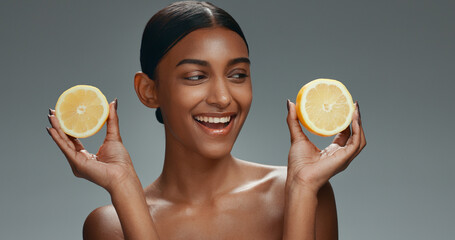 Beauty, skincare and happy woman in studio with lemon, natural cosmetics isolated on grey...